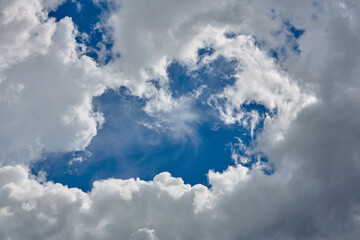 Cumulus clouds against a light blue sky with a clear fiber structure.