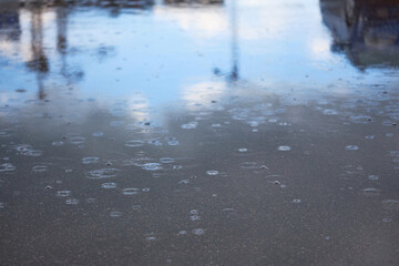 Naklejka na ściany i meble Heavy rain falling on the asphalt, puddles with splashes from drops..