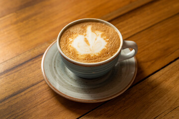 Beautiful mug with hot cappuccino on the wooden table