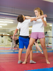 Fototapeta premium Preteen children working in pair mastering new self-defense moves at gym