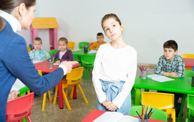 Female teacher scolding naughty student in elementary school class - obrazy, fototapety, plakaty