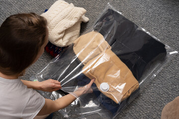 Transparent vacuum bag with warm things for seasonal storage on a blanket. Space saving concept,...