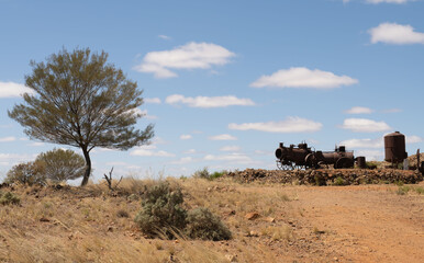 Desert scene near Silverton, New South Wales, Australia. Old rusty steam engine and boiler previously used for mining and mulga trees.