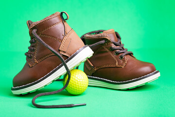 children's leather shoes with laces and a ball on a green background. Close-up.