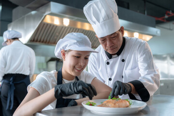 Male chefs train female apprentices in a cooking class.