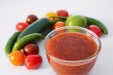 Bowl with delicious salsa sauce and ingredients on white background, closeup