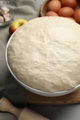Fresh yeast dough, rolling pin and ingredients on grey table, closeup. Making cake