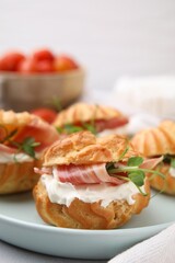 Delicious profiteroles with cream cheese and prosciutto on plate, closeup