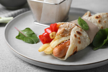 Delicious pita wrap with sausage, french fries and pepper on light gray table, closeup