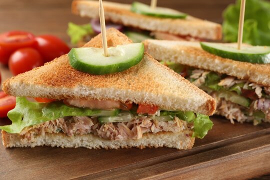 Delicious sandwiches with tuna and vegetables on wooden board, closeup