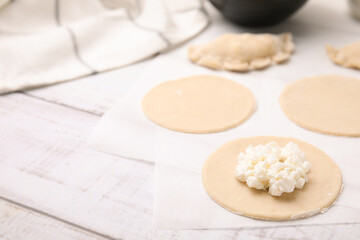 Fototapeta na wymiar Process of making dumplings (varenyky) with cottage cheese. Raw dough and ingredients on white wooden table, closeup. Space for text