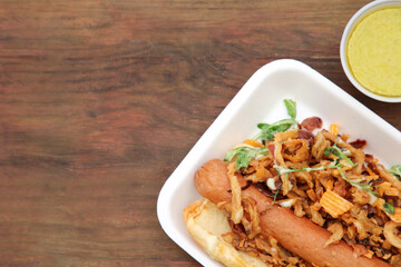 Fresh delicious hot dog with sauce on wooden table, flat lay. Space for text