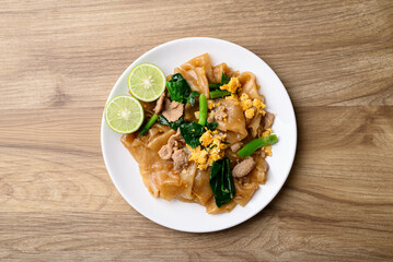 Thai food (Pad See Ew), Stir fried rice noodles soy sauce with pork, egg and kale on wooden background, Table top view
