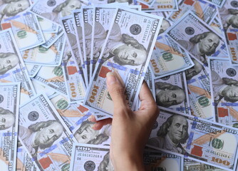 Top view of hand holding fan of dollar money on 100 dollar bills. 