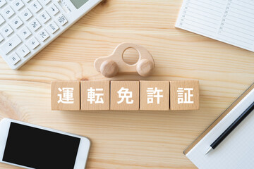 運転免許証と書かれたブロック、車のおもちゃ、スマホ、電卓、ノート