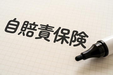 自賠責保険と書かれたノートとマーカー