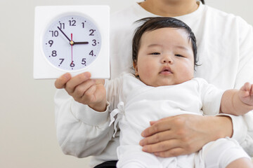 母親の膝抱っこされる赤ちゃんと時計（0歳4か月、日本人、男の子）