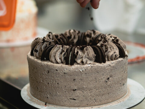 preparing brown frosted icing cup cake with cookies on top