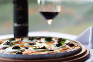 Pizza servida na mesa de um restaurante com vinho acompanhando