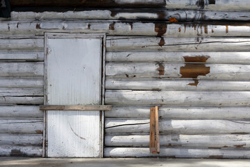 An image of a barred door on an old log cabin with white wash paint.