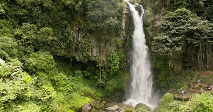 Waterfall among tropical jungle with green plants and trees. Sikulikap Falls. Sumatra, Indonesia.