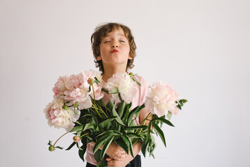 Cheerful happy child with Peonys bouquet. Smiling little boy on white background. Mother's Day....