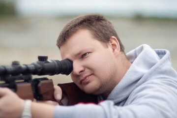 man aims at an optical sight for shooting from a rifle