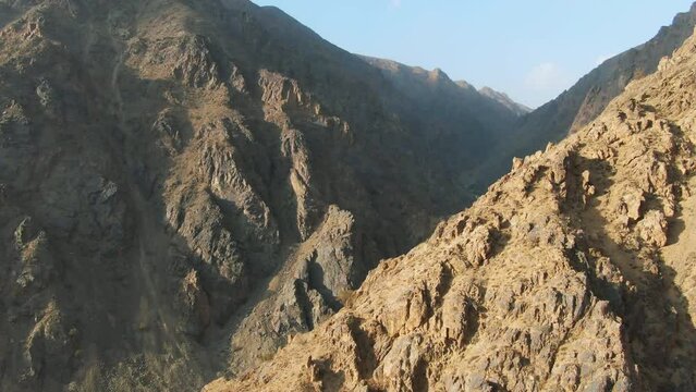 Forward aerial of stony mountains at golden hour in rural Afghanistan