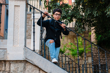 Young transgender person smiling while posing standing on stairs outdoors.