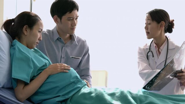 Asian doctor visit patient woman and suggest physical examination of looking picture ultrasound scanning at hospital. Concept of family, medical, healthcare and technology.