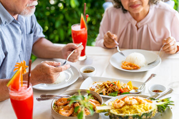 Happy Asian family senior couple having lunch and sharing meal together at restaurant. Elderly...