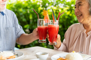 Happy Asian family senior couple having lunch and sharing meal together at restaurant. Elderly people man and woman enjoy retirement with outdoor activity lifestyle on summer holiday travel vacation.