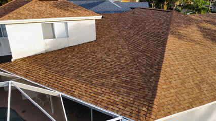 Red Residential tile shingle roof with second floor of Florida house during sunset from aerial drone