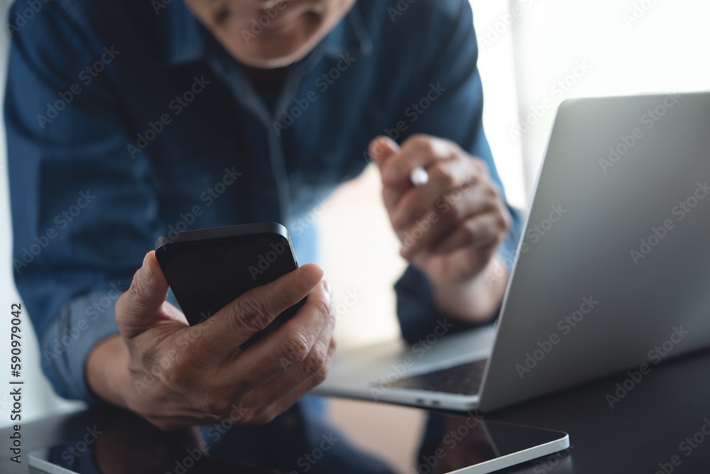 Wall mural close up of business man using mobile smart phone and working on laptop computer with digital tablet