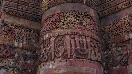 A fragment of the highest brick minaret Qutub Minar. Close-up. Elegant ornaments and patterns are carved on the red sandstone. India. Delhi