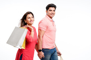 Young indian couple holding shopping bags on white background.