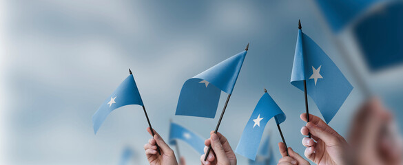 A group of people holding small flags of the Somalia in their hands