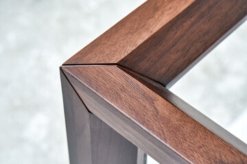 Wooden frame of bedside table made of solid walnut in workshop. Joinery angular joint of planks on...