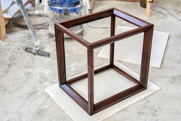 Wooden frame of bedside table made of solid walnut in workshop. Joinery angular joint of planks on dowels