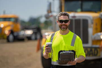 Builder with cup of coffee. Construction engineer worker in builder uniform near construction...