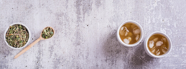 Iced green japanese hojicha tea in cups and leaves in a bowl  top view web banner