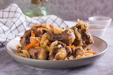 Stewed oxtail with carrots and onions on a plate on the table - obrazy, fototapety, plakaty