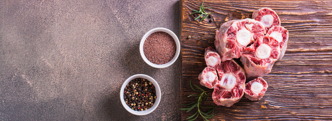 Pieces of raw oxtail and spices for cooking on a wooden board on the table top view web banner
