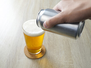 机の上の缶ビールをグラスに注ぐ