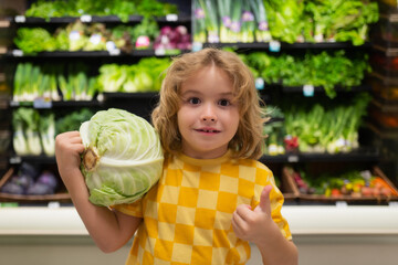 Fototapeta premium Child with cabbage. Child choosing fruits and vegetables during shopping at vegetable supermarket.