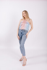 Posh fashionable confident slim blond long haired woman standing and posing in colorful casual clothes in white studio