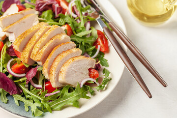 Chicken breast on the leaves arugula with radichio, tomatoes and onions. Balanced lunch.