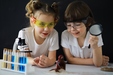 Children scientists. Schoolchildren in the laboratory conduct experiments. Boy and girl experiments with a microscope.