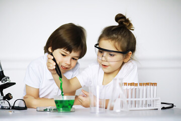 Two cute children at chemistry lesson making experiments on white background