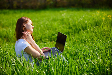 Portrait of beautiful young woman on nature with laptop